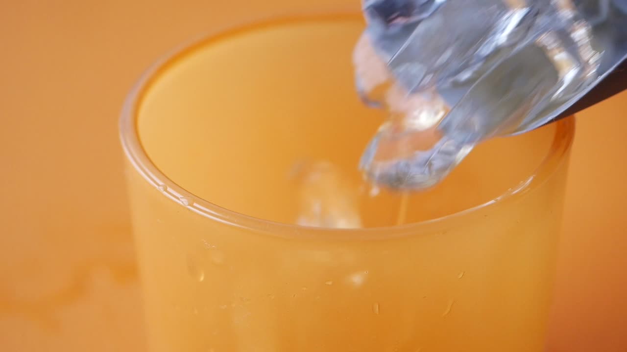 오렌지 주스 한 잔 에 얼음 큐브 가 첨가 되고 있다