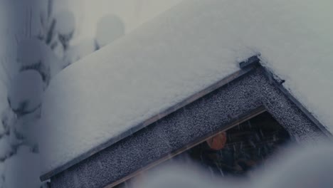 house-roofed thickly covered with snow during snowstorm. close-up