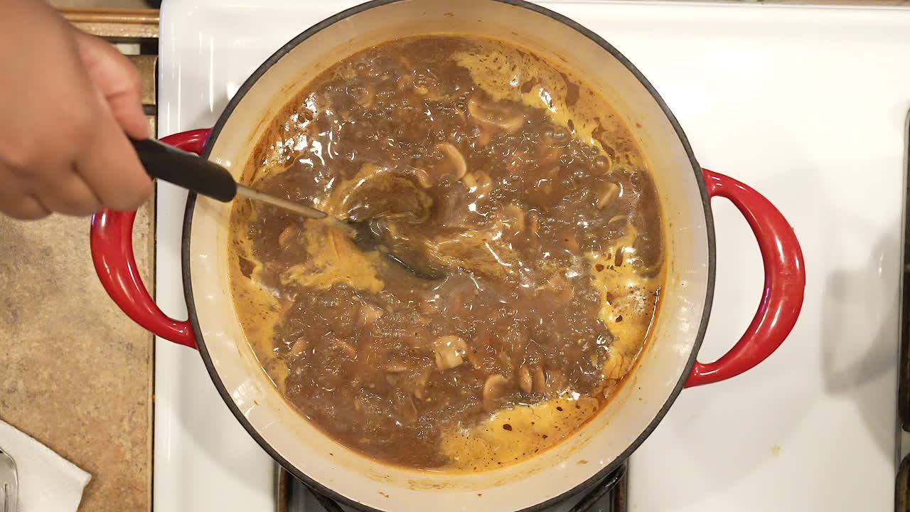 revolviendo arroz salvaje vegano y sopa de champiñones mientras hierve en la estufa - vista aérea en cámara lenta serie de arroz salvaje