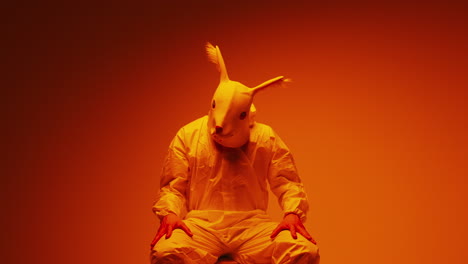 person wearing rabbit mask and protective suit in orange light