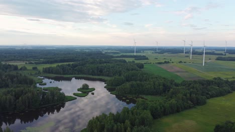 Beautiful-landscape-with-lake-and-green-forest-and-many-wind-turbines,-aerial