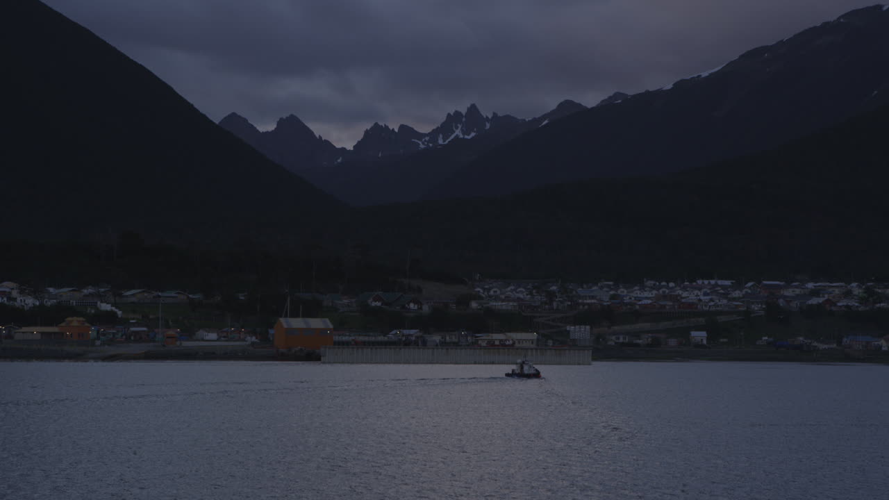 Città sull'oceano con montagne sullo sfondo, tramonto