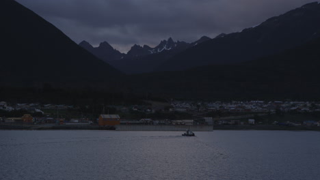 ciudad en el océano con montañas al fondo, puesta de sol