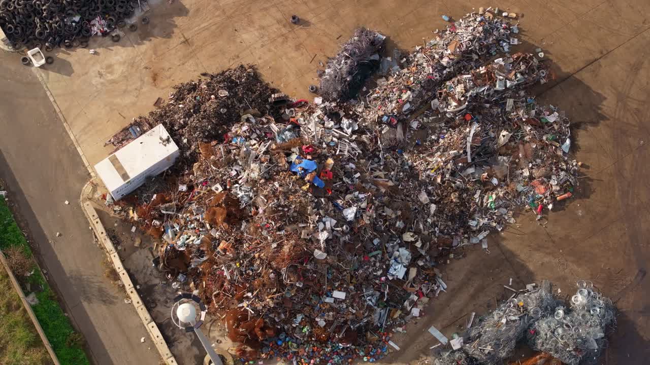 Vista drone di gru che spostano cumuli di rottami metallici in un centro di riciclaggio