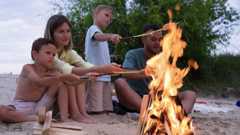 family eating sausages on the beach