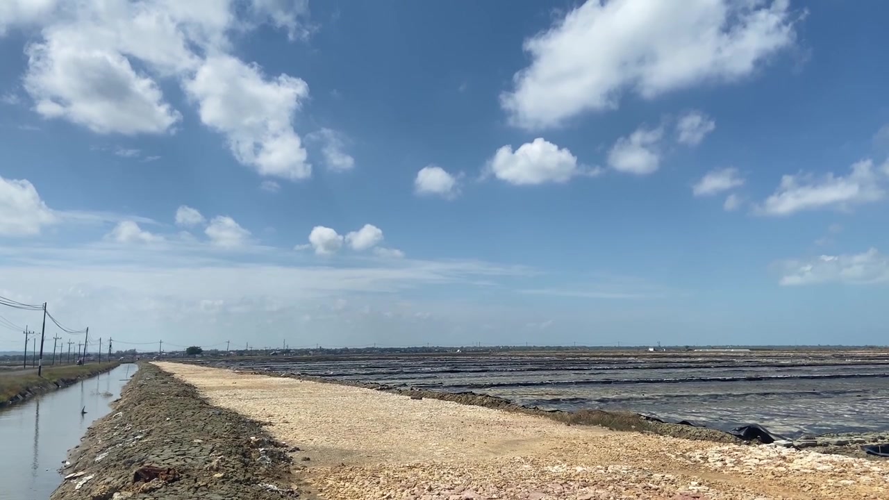 青空と白い雲が広がる広大な塩田の風景