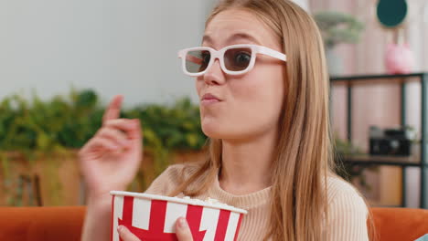 Woman-sitting-on-couch-eating-popcorn-and-watching-interesting-TV-3D-film,-sport-game-online-at-home