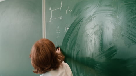 little boy erasing chalkboard.