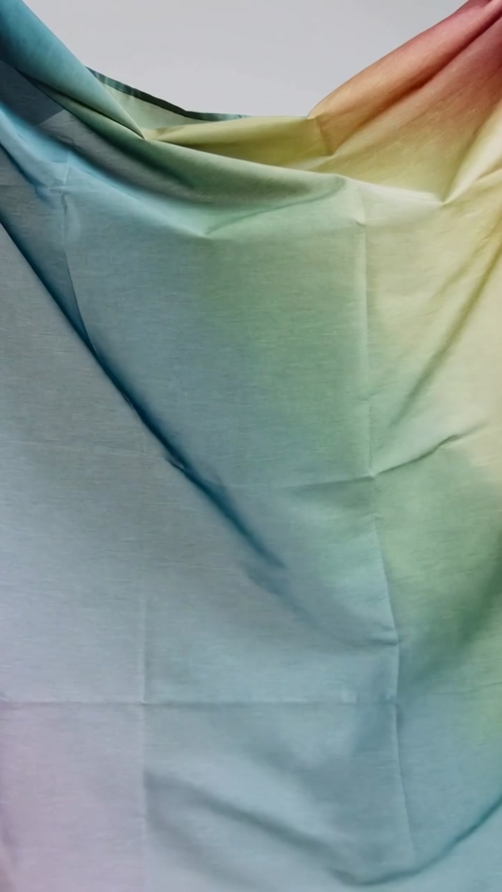 Vertical video: Lifting top edge causing gradient fabric smoothing in studio, showing teal to pink