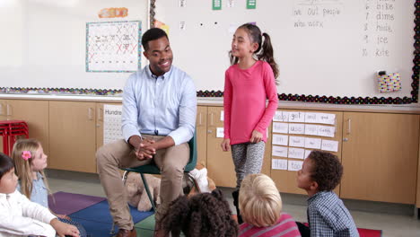 hispanic schoolgirl standing with teacher in front of class