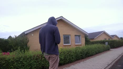 hooded man walking on a sidewalk.