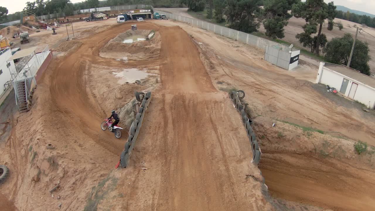 Piloto de motocross saltando sobre uma rampa de terra em um circuito