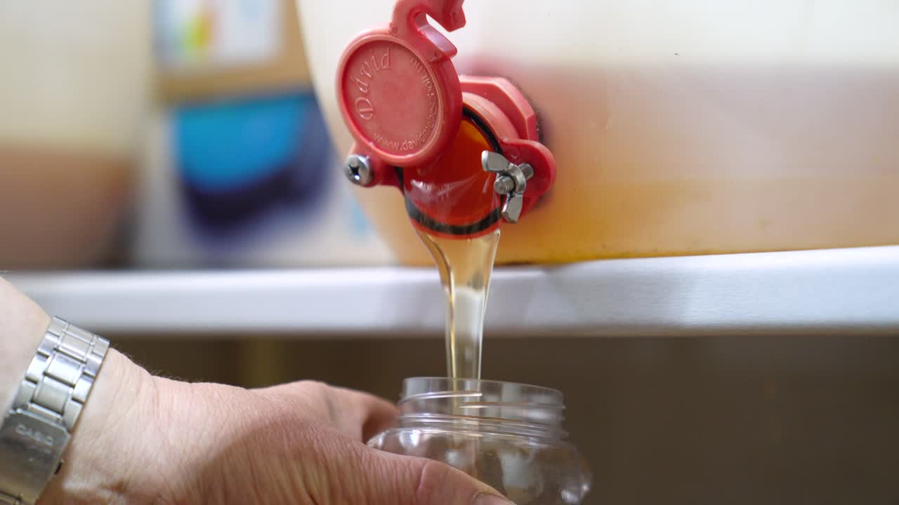 Getting Fresh Pure Honey In A Bucket With A Gate. Rack Focus Shot