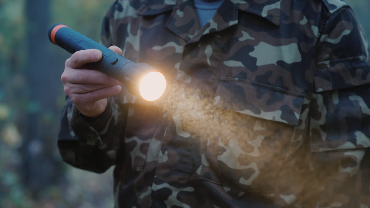 мужчина освещает себе путь фонариком в тумане крупным планом