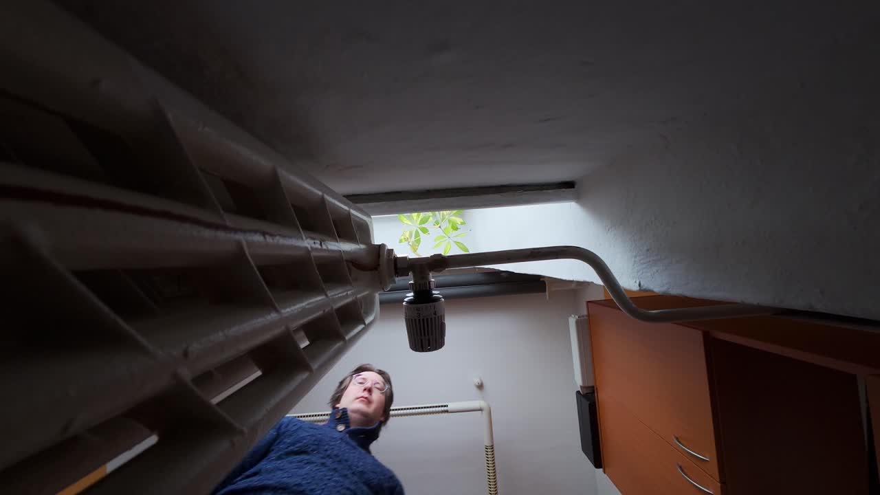 Turning up the heating in winter and trying to warm up. A man in an apartment regulates the central heating