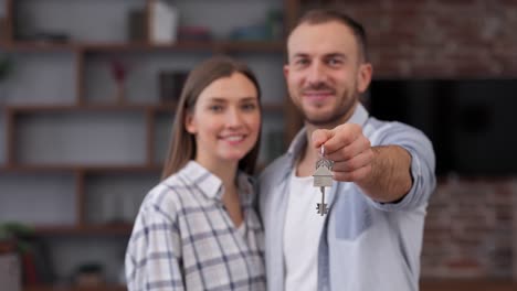 young couple showing bunch of keys from new house on camera. happy homeowners on relocation day. real estate and tenancy concept. loan mortgage for young family.