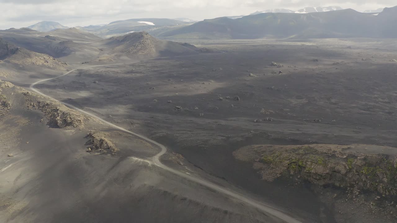 toma aérea inclinada hacia arriba de una carretera abandonada entre un paisaje áspero de arena negra en la isla de islandia