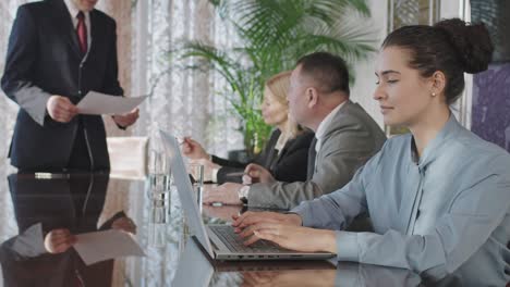 business woman in a business meeting in the office, uses laptop while looking at camera