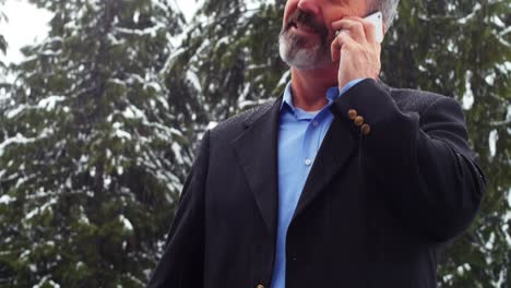 man talking on the phone and charging the electric car on a snowy day