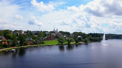 calm lakeside drone shot with distant view of the church and town across the water, under scattered clouds. shot in zarasai, lithuania
