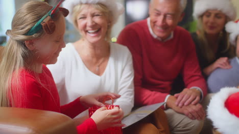 familia de varias generaciones intercambiando y abriendo regalos alrededor del árbol de navidad en casa