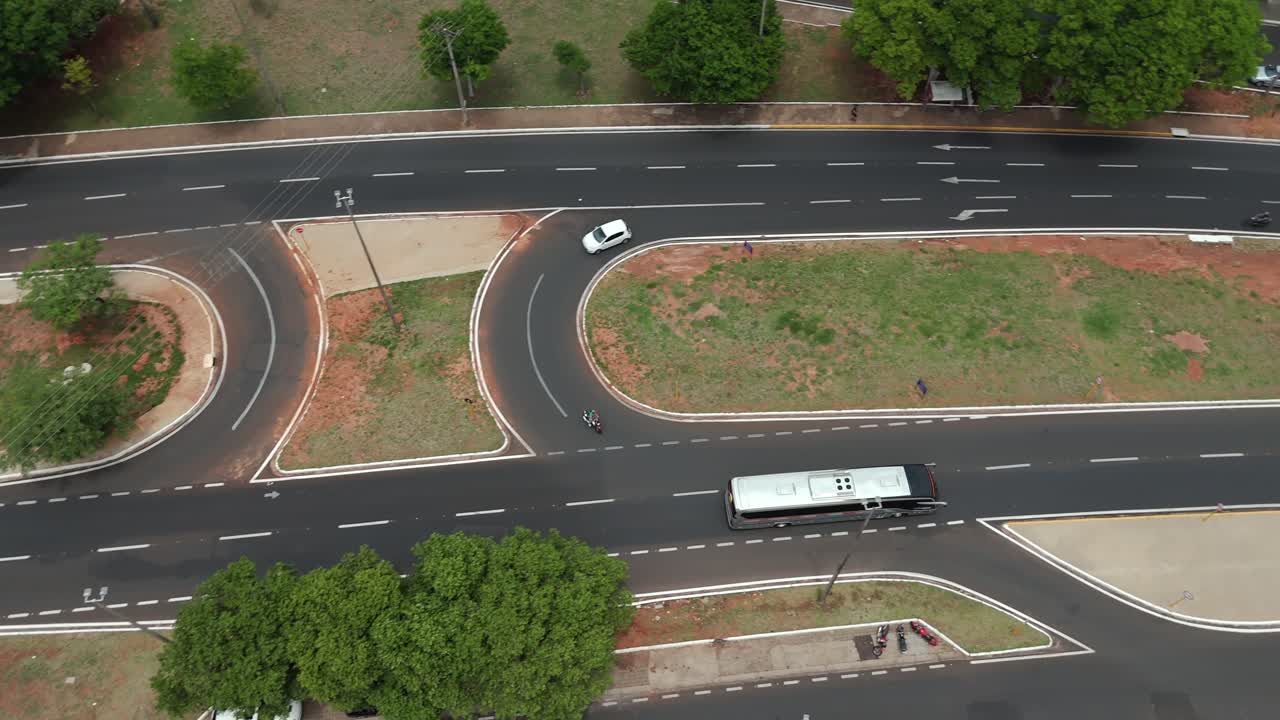 Aerial birdseye tracking shot of bus traveling along avenue on sunny day