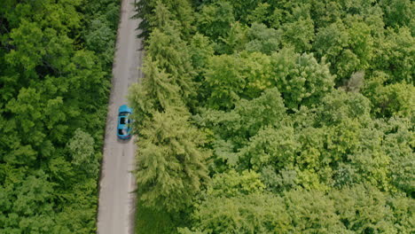 aerial view of modern automobile on the road in forest. blue car driving on the forest road.