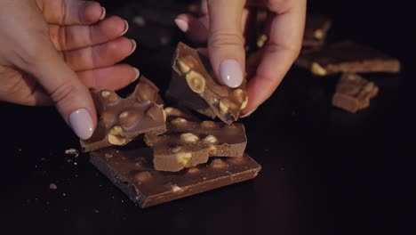 Woman-breaks-black-chocolate-bar-with-nuts.-Close-up.-Slow-motion