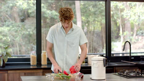 man chopping vegetables in modern kitchen, preparing meal with fresh ingredients
