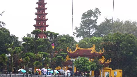 people with umbrellas at tran quoc pagoda