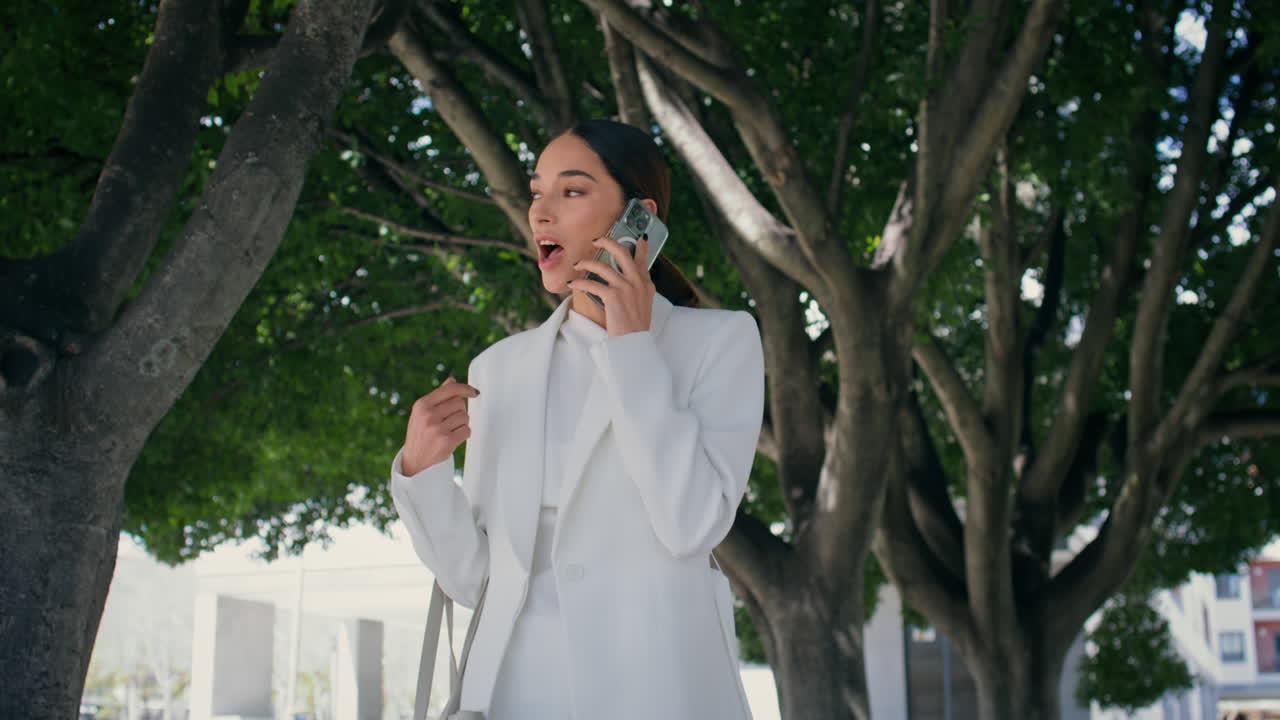 멋진 사업가 여성이 전화를 하고 나무 에서 고 있습니다. 여성이 전화로 이야기하고 있습니다.