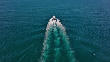 largo rastro blanco de una lancha rápida que navega sobre el tranquilo agua azul del mar