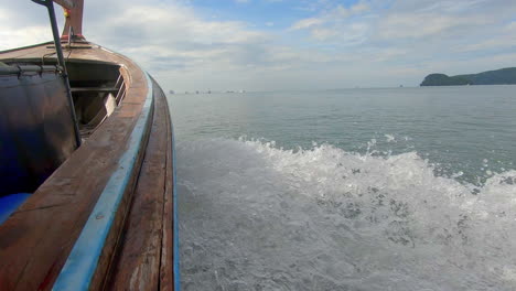 slow motion | wake coming off wooden boat in thailand with islands in the distance