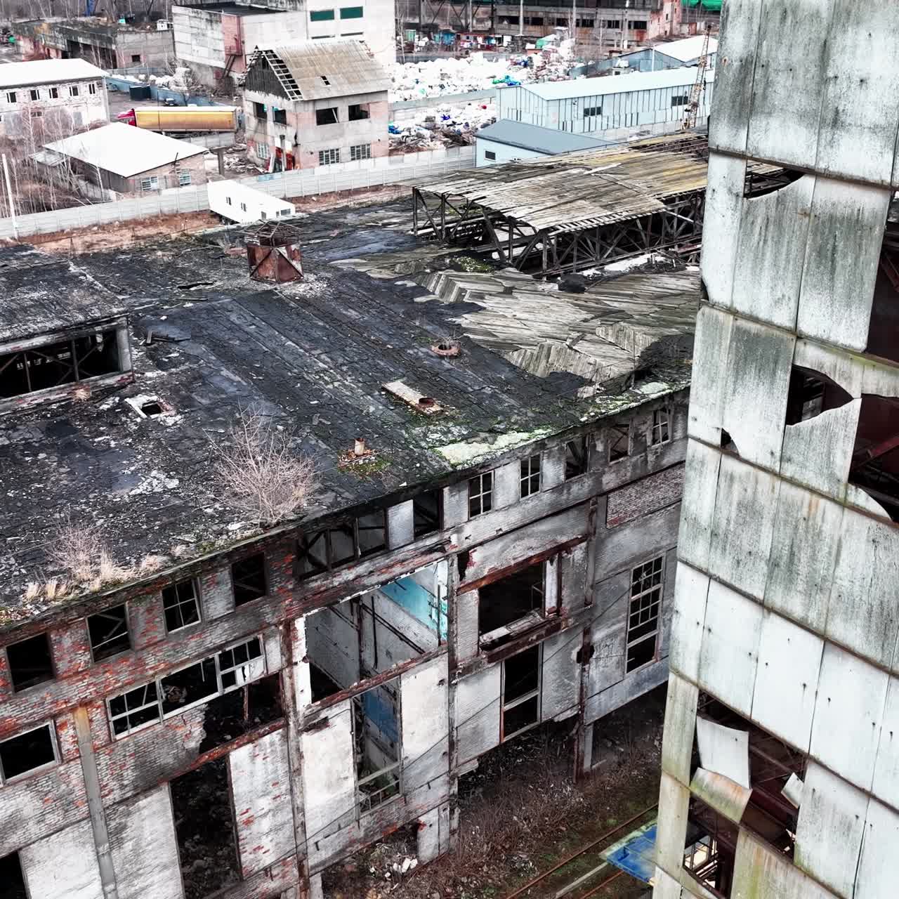 Decayed exterior of an old chemical factory complex. Grey ruined walls and roofs of the buildings from aerial perspective
