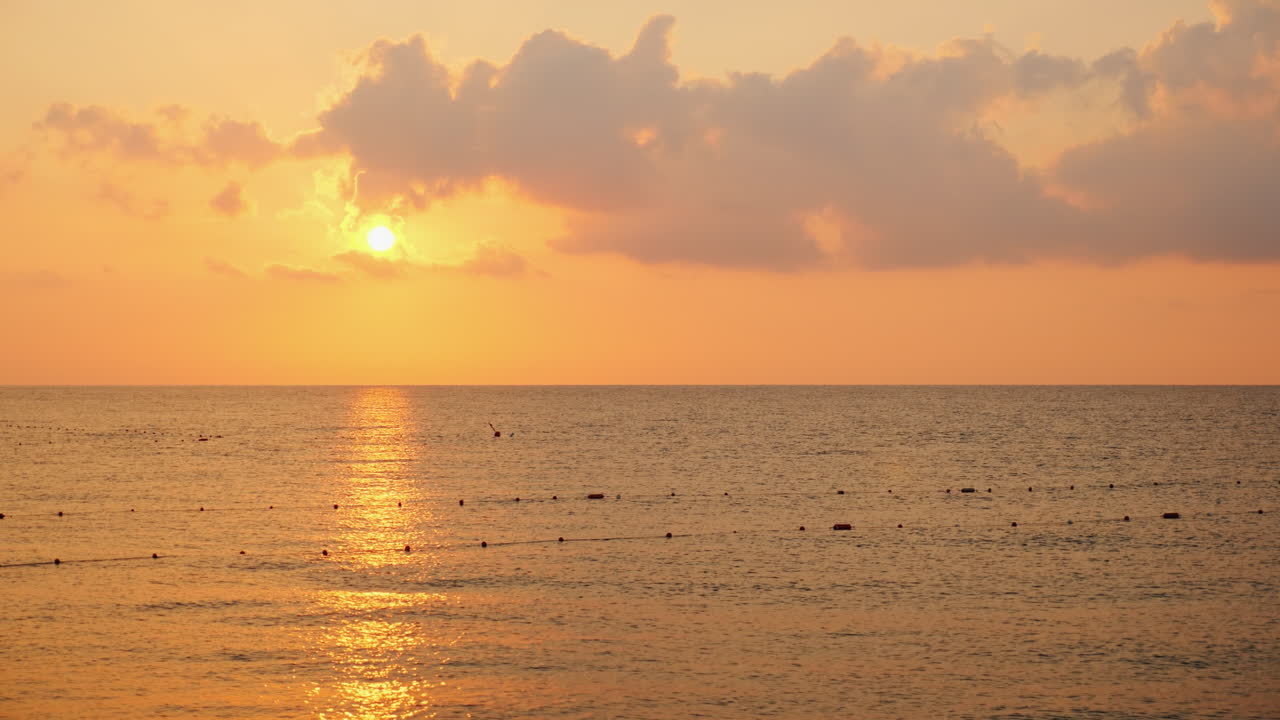 해가 바다 위로 떠오르며 극적으로 아름다운 구름을 분홍빛으로 비추고 있다