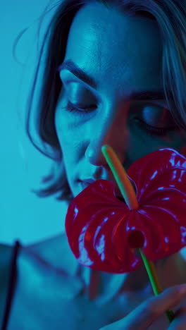 woman with red anthurium under neon lighting