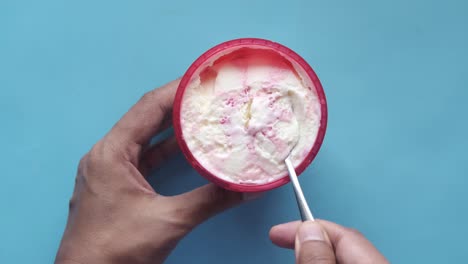 comiendo helado de vainilla de fresa de una taza roja