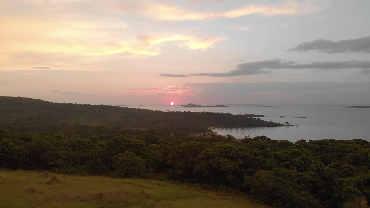 toma aérea avanzando sobre el paisaje africano con el amanecer naranja sobre el lago victoria