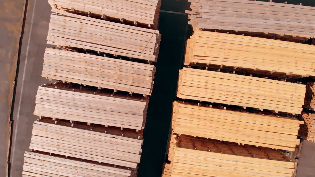 Lumber materials outdoods in the sun. Piles of wooden planks at the territory of modern door producing company.