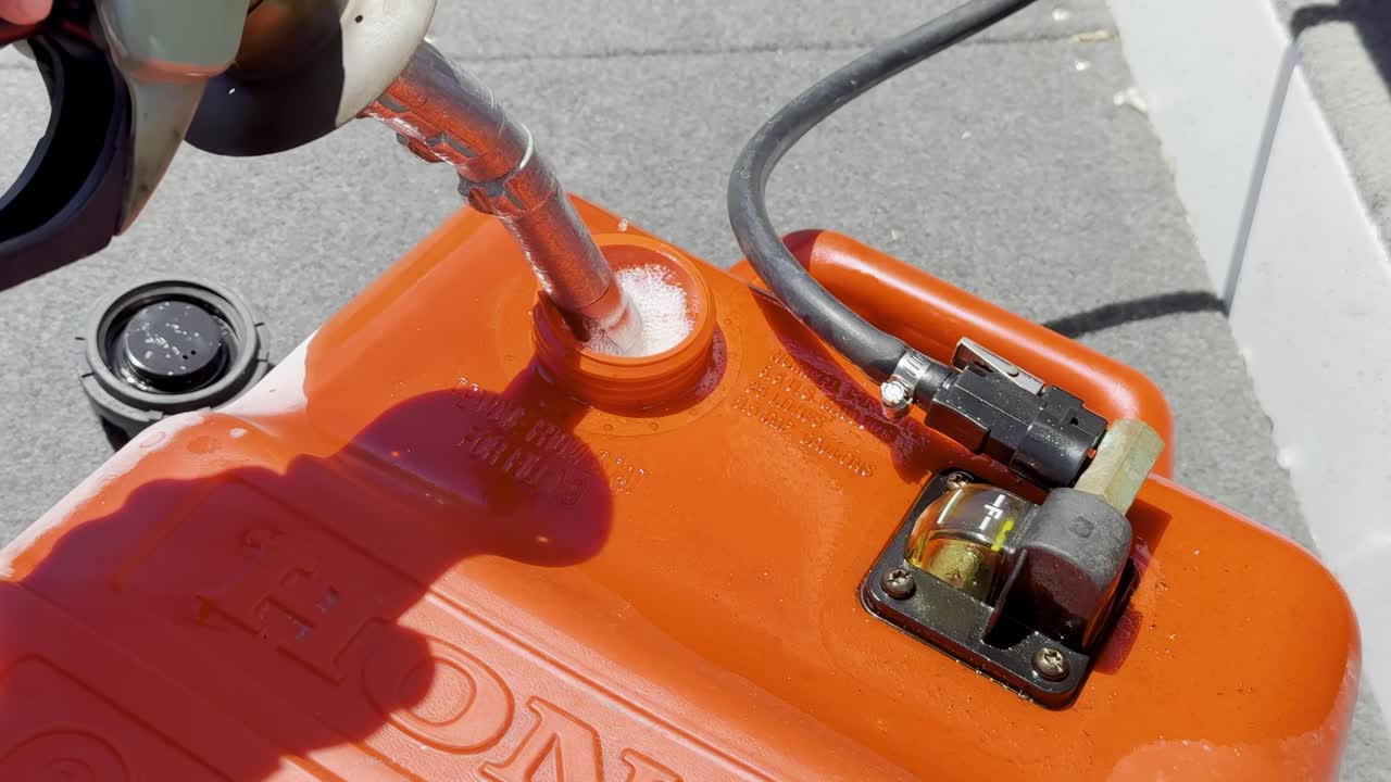 Close-up of a fuel nozzle refilling an orange container, showing detailed equipment and liquid handling.