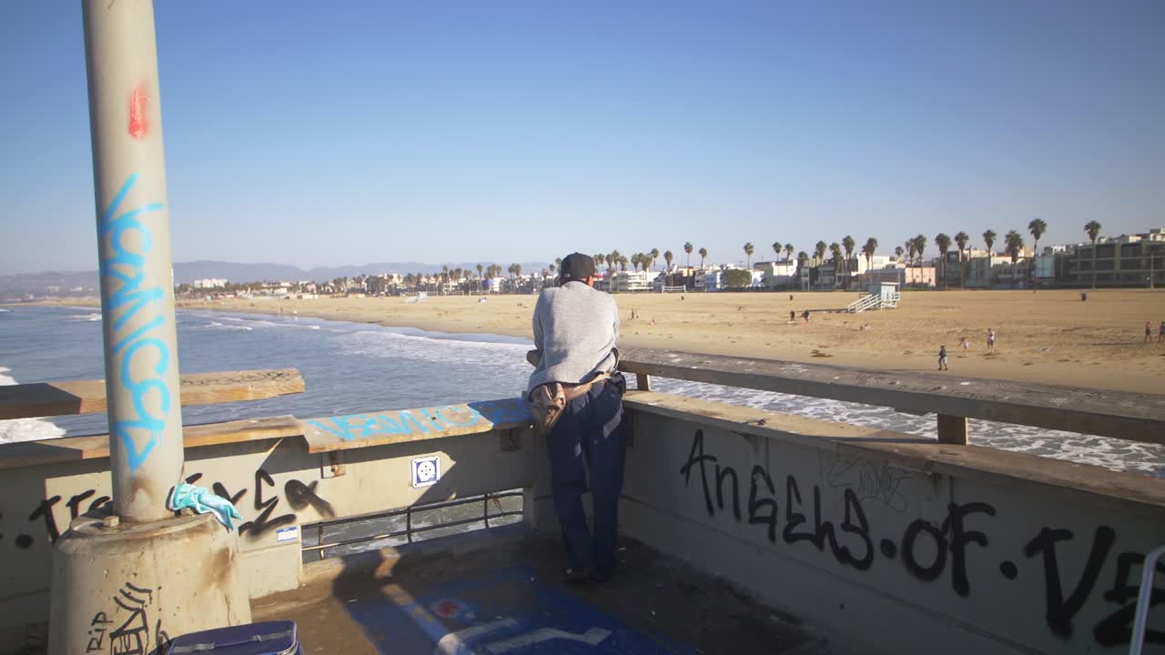 부두에서 베니스 해변을 바라보는 남자