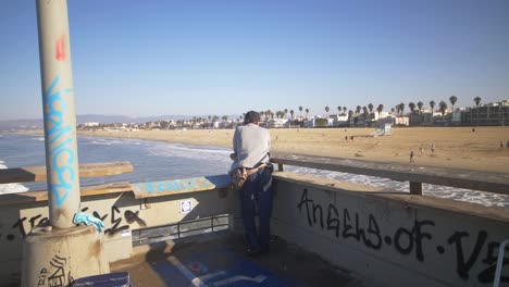 hombre mirando la playa de venice desde el muelle