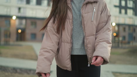 close-up shot focusing on the legs of a girl wearing black trousers and a peach jacket as she rolls on rollerblades through an urban park path. the smooth motion and urban environment