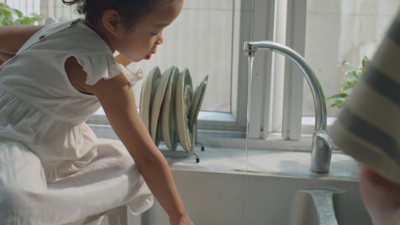 Asian Toddler Girl Playing as Mom Doing Dishes