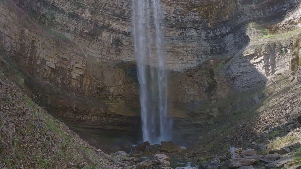 Majestetisk foss fosser ned en steinete klippe i et rolig basseng nedenfor i naturlige omgivelser.