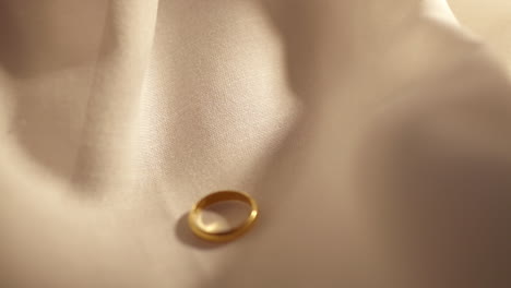 letting a gold ring slide over a cream colored cloth, a precious piece of jewelry