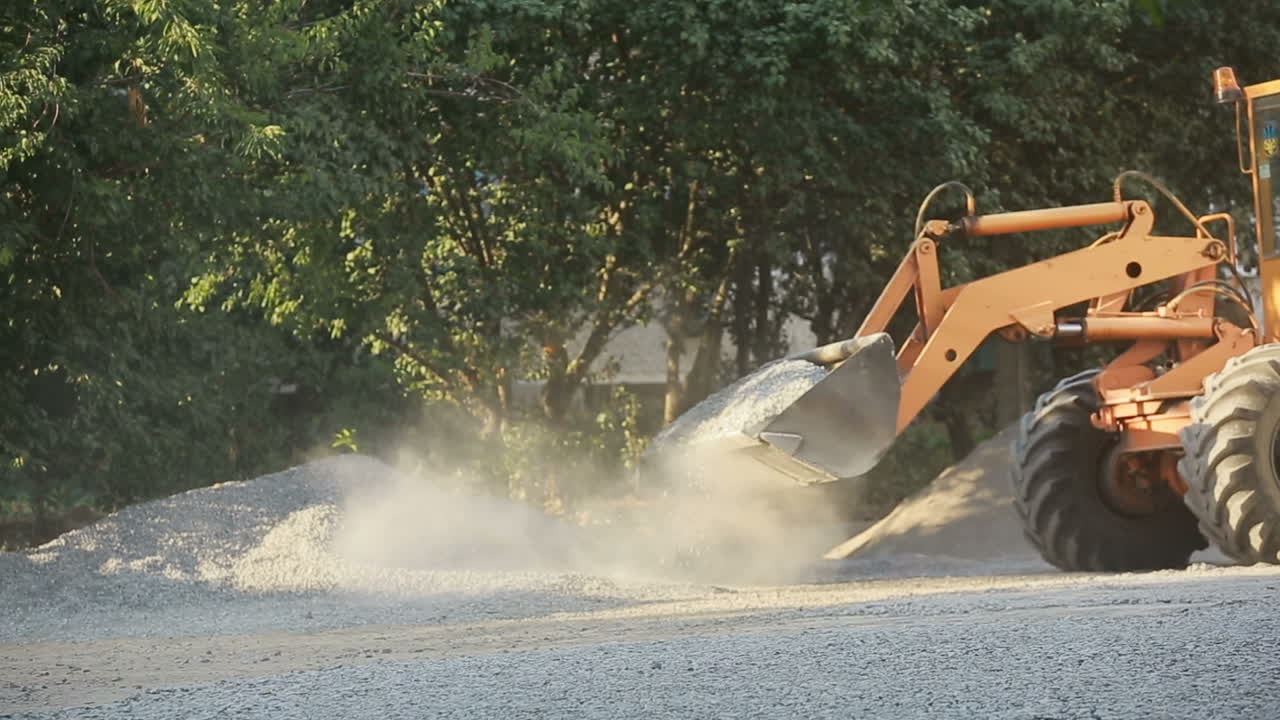 Construction worker holding shovel with gravel working on road construction