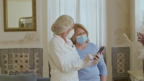 Doctor-and-patient-looking-at-phone-after-vaccination-at-home