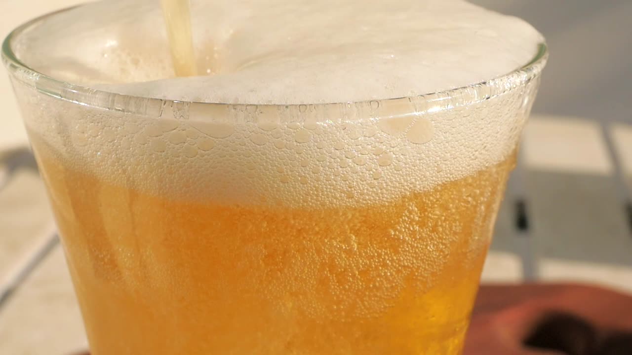 parte superior del vaso de cerveza en primer plano mostrando todas las pequeñas burbujas y espuma blanca brillante.