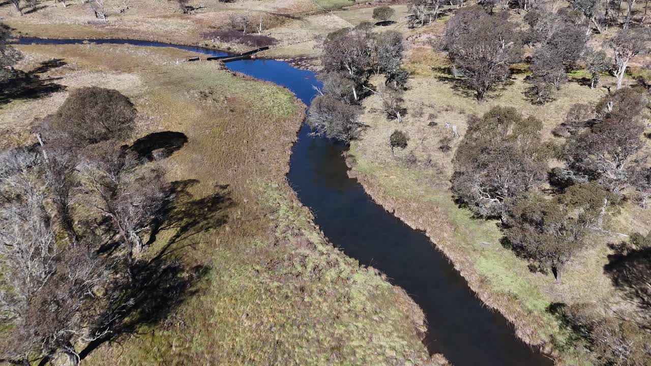 Drone footage of winding stream through rural Australian landscape
